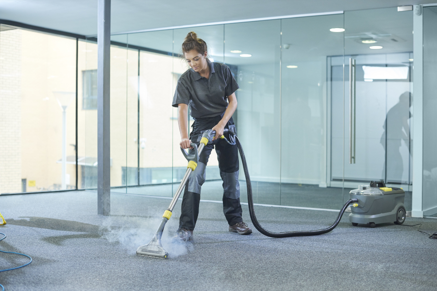 Eine Frau reinigt den Teppichboden eines Bürogebäudes im Rahmen einer Baureinigung.